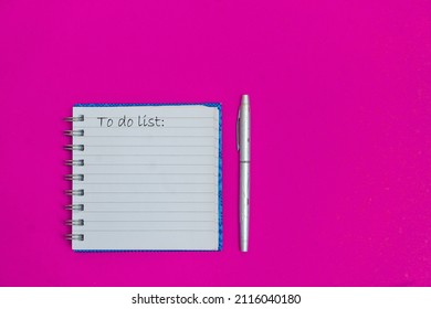 To do list on the pink table with pen. Planning and organization of work. Plat lay place for text