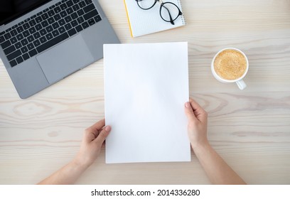 To Do List Or Organizing Plans. Woman Holding White Empty Sheet Of Paper, Sitting At Desk With Laptop Computer And Cup Of Coffee, Top View, Flat Lay