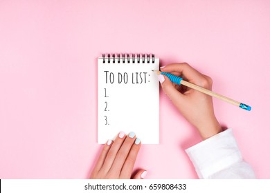 To do list in spiral notepad. Trendy pink background, flat lay style.