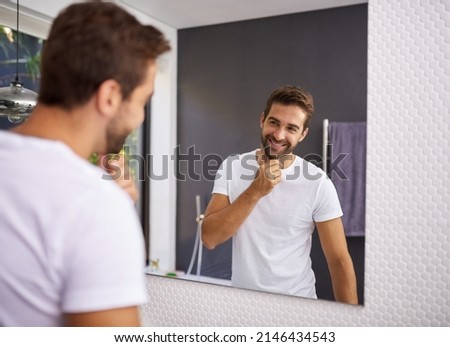 I do look good with a beard though. Cropped shot of a handsome man looking at himself in the mirror whilst touching his beard at home.