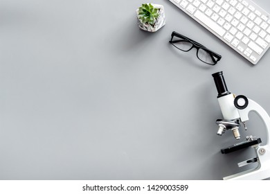 Do Medical Research On Laboratory Desk With Microscope, Keyboard, Glasses On Gray Background Top View Mockup