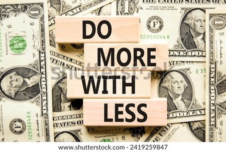 Do more with less symbol. Concept word Do more with less on beautiful wooden block. Dollar bills. Beautiful background from dollar bills. Business do more with less concept. Copy space.