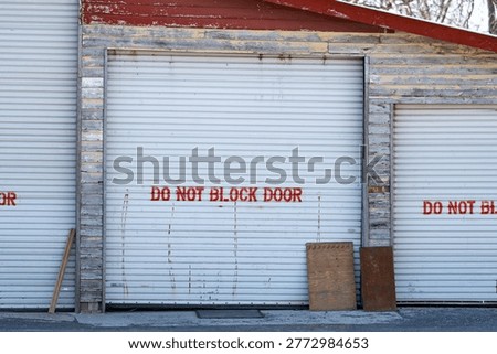 Do not block door painted message on a garage bay. The door is metal and the building has wood siding.