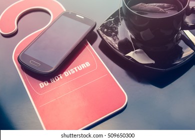 Do Not Disturb Sign, A Cup Of Tea And A Mobile Phone Over Dark Background. Time For Rest Concept.