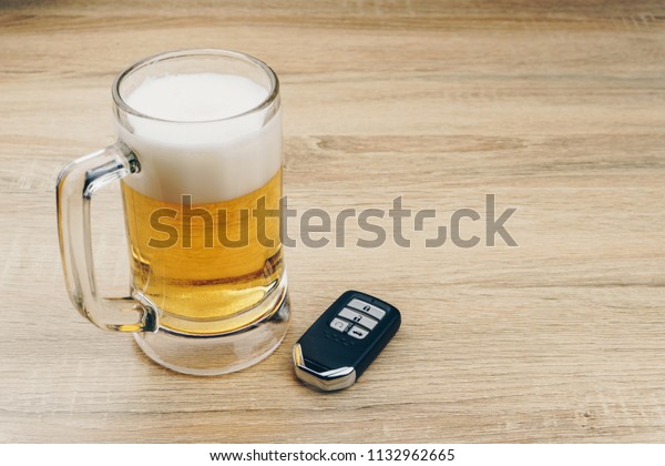 do not drink and drive concept,\
close up of a mug of beer and a remote car key on wooden\
table