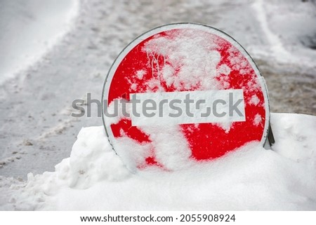 Do not enter road sign. Car traffic prohibited. Warning no entry zone. Drive in forbidden. No entry - road sign during snowfall, covered with snow