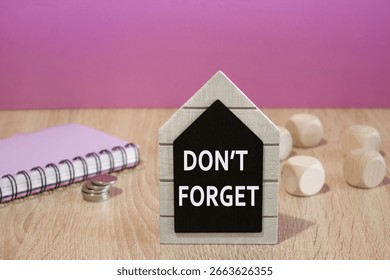 Do not Forget Reminder Note symbol. Concept words Do not Forget Reminder Note on a black board. Beautiful purple background. Notebook and silver coins on the table. Business concept. Copy space.