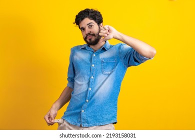 I Do Not Have More Money. Portrait Of Sad Bankrupt Bearded Young Man In Blue Casual Style Shirt Standing And Showing Empty Pocket And Looking At Camera. Indoor Studio Shot, Isolated On Yellow 