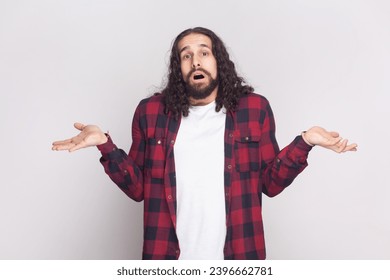 I do not know. Unaware perplexed bearded man spreads palms sideways, has no idea what to do, thinks how to act in troublesome situation. Indoor studio shot isolated on gray background.