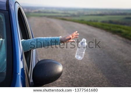 Do not pollute nature with plastic waste!  Driver throwing away plastic bottle from car window. Environmental conservation