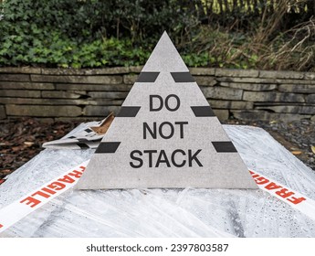 A do not stack cardboard sign in the shape of a pyramid on top of a delivery.