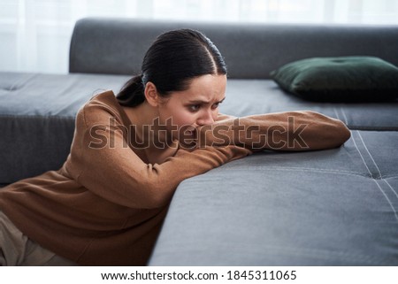 Do not touch me. Negative delighted woman laying with head on the sofa and crying while feeling bad. Depression and bad mood concept