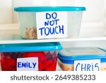 Do Not Touch sticker on lunch boxes in office refrigerator. Angry and hungry workers concept.