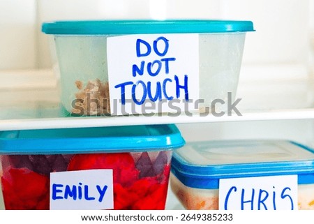 Do Not Touch sticker on lunch boxes in office refrigerator. Angry and hungry workers concept.