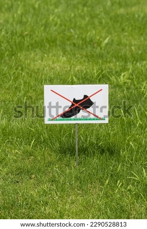 Do not walk on the grass sign placed on a beautiful green lawn. Forbidding sign close-up