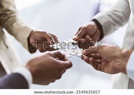 Do you see the bigger picture. Closeup shot of a group of unrecognizable businesspeople joining puzzle pieces together in an office.