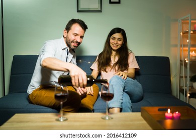 Do You Want More Wine? Romantic Latin Man In His 30s Pouring A Glass Of Red Wine For Her Girlfriend During A Casual Date At Home