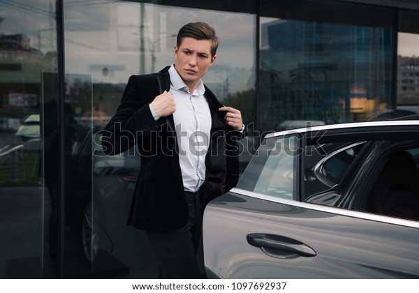 Do your own business! A handsome young businessman\
walking to his car on the street, while adjusting his jacket before\
sitting into.