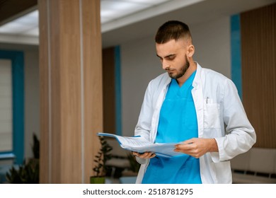 Doc reviewing patient files indoors. A healthcare worker in scrubs studies patient files while standing in a modern medical facility during the day. - Powered by Shutterstock