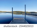 A dock looking out at the reflection of fall leaves on calm water. 