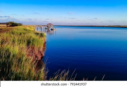 Dock on Daufuskie Island in Beaufort, South Carolina surrounded by marsh and deep blue waters from the intercoastal waterway.