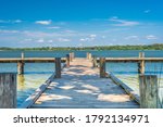 Dock on a lake with blue skies and some small clouds.