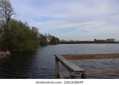 dock on the lake in the evening with green trees on edge of pond with relaxing soothing area blue and white clouds in the sky lakeside view Minnesota park - Powered by Shutterstock