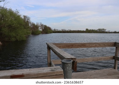 dock on the lake in the evening with green trees on edge of pond with relaxing soothing area blue and white clouds in the sky lakeside view Minnesota park - Powered by Shutterstock