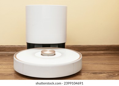 Dock station of a robot vacuum cleaner inside a house near a yellow wall on a wooden floor - Powered by Shutterstock