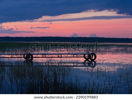 Dock at sunset dusk with a magenta color cast in clouds and water with water reflection taken in the Chippewa National Forest, northern Minnesota USA
