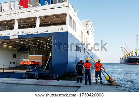 Dock workers pulling ship rope