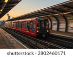 Docklands Light Railway (DLR) train waiting at West Silvertown station platform during sunset, in London, UK