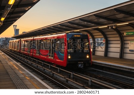 Docklands Light Railway (DLR) train waiting at West Silvertown station platform during sunset, in London, UK