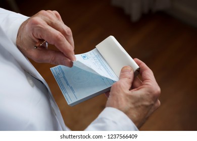 A Doctor About To Tear Off A Prescription From A Prescription Pad.

