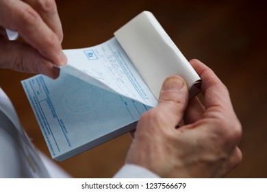 A Doctor About To Tear Off A Prescription From A Prescription Pad.

