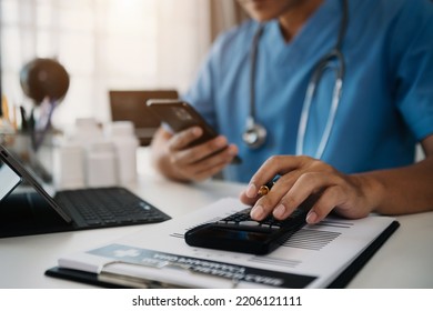 Doctor Or Accounting Department Writes A Note And Uses A Calculator To Calculate Expenses - Income. Of Hospital Staff.