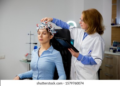 Doctor Adjusting Neurology Headset By Looking At Tablet. Brain Scan Procedure