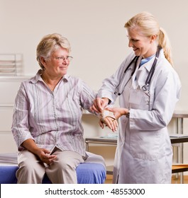 Doctor Adjusting Senior Woman Wrist Splint