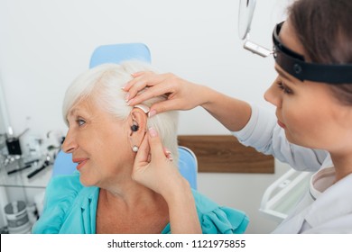 doctor adjustment of hearing aids for the elderly patient, at medical office - Powered by Shutterstock