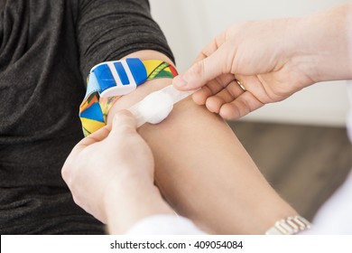 Doctor Applying Bandage On Patient's Hand After Blood Test