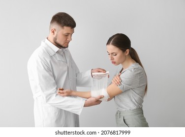 Doctor applying bandage onto arm of young woman on light background - Powered by Shutterstock