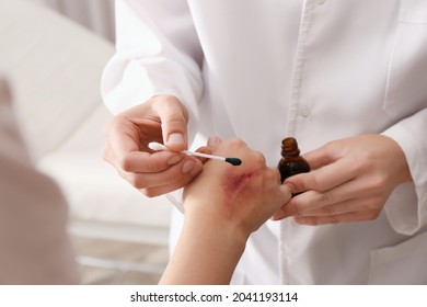 Doctor Applying Brilliant Green Onto Injured Hand Indoors, Closeup