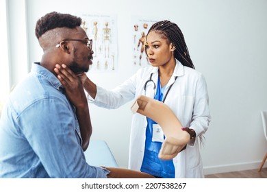 Doctor Applying Cervical Collar On Neck Of African American Man In Clinic. Female Doctor Putting Neck Orthopaedic Collar On Adult Injured Man. Man In Pain At The Doctor For A Neck Injury