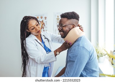 Doctor Applying Cervical Collar On Neck Of African American Man In Clinic. Female Doctor Putting Neck Orthopaedic Collar On Adult Injured Man. Man In Pain At The Doctor For A Neck Injury