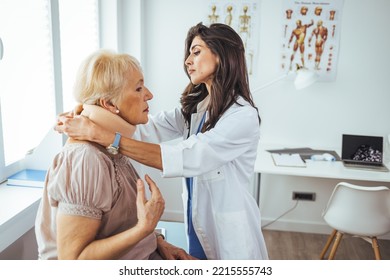 Doctor Applying Cervical Collar On Neck Of Senior Woman In Clinic. Female Doctor Putting Neck Orthopaedic Collar On Adult Injured Woman. Woman In Pain At The Doctor For A Neck Injury