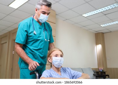 Doctor or assistance staff wear face mask and help a elder patient woman while sitting on wheelchair in the hospital, coronavirus pandemic protection - Shutterstock ID 1865692066