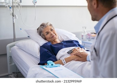 Doctor assuring senior woman patient lying on hospital bed. Happy elderly patient lying on hospital bed feeling relaxed after doctor giving health update. Physician examining hospitalized mature woman - Powered by Shutterstock