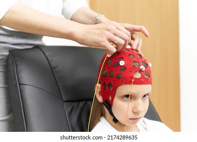 Doctor Attaching Electrodes To A Girl's Headgear For Biofeedback Therapy