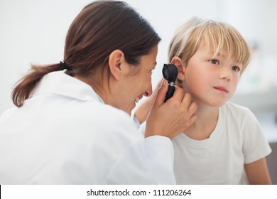 Doctor auscultating the ear of a child in examination room - Powered by Shutterstock