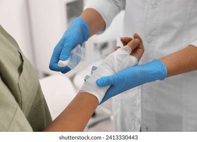 Doctor bandaging patient's burned hand indoors, closeup - Powered by Shutterstock